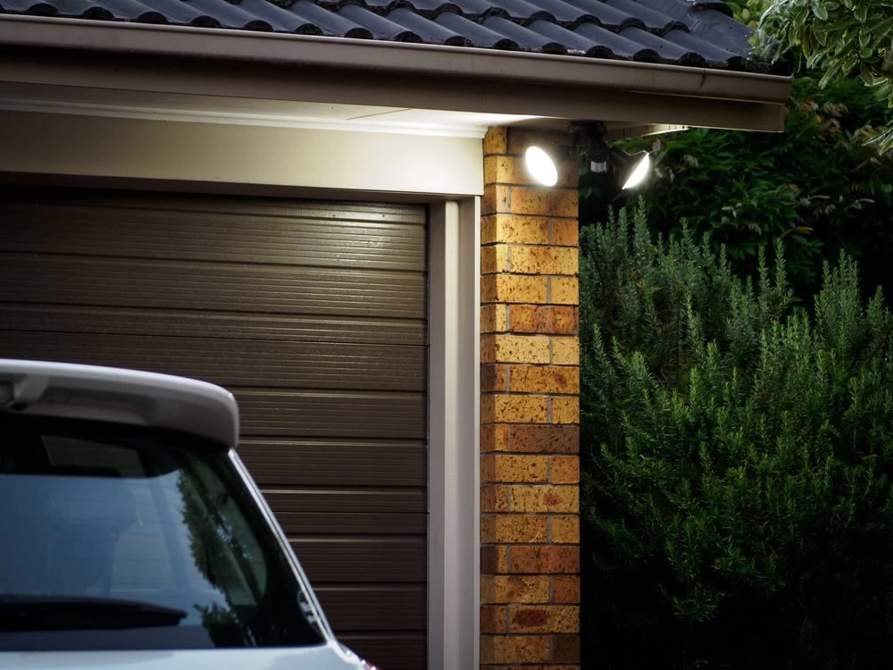 Garage Security Light - Taylor County, TX | Hooked Up Electric A car parked outside a garage with two lights on, showcasing a well-lit evening scene in Taylor County, Texas, where Hooked Up Electric provides reliable electrical services
